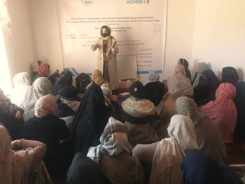 Women attend a session in front of a UN Women programme banner.
