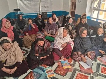 Women seated with notebooks during a training session.