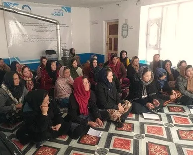 Women seated in a training room with programme banners on the wall.